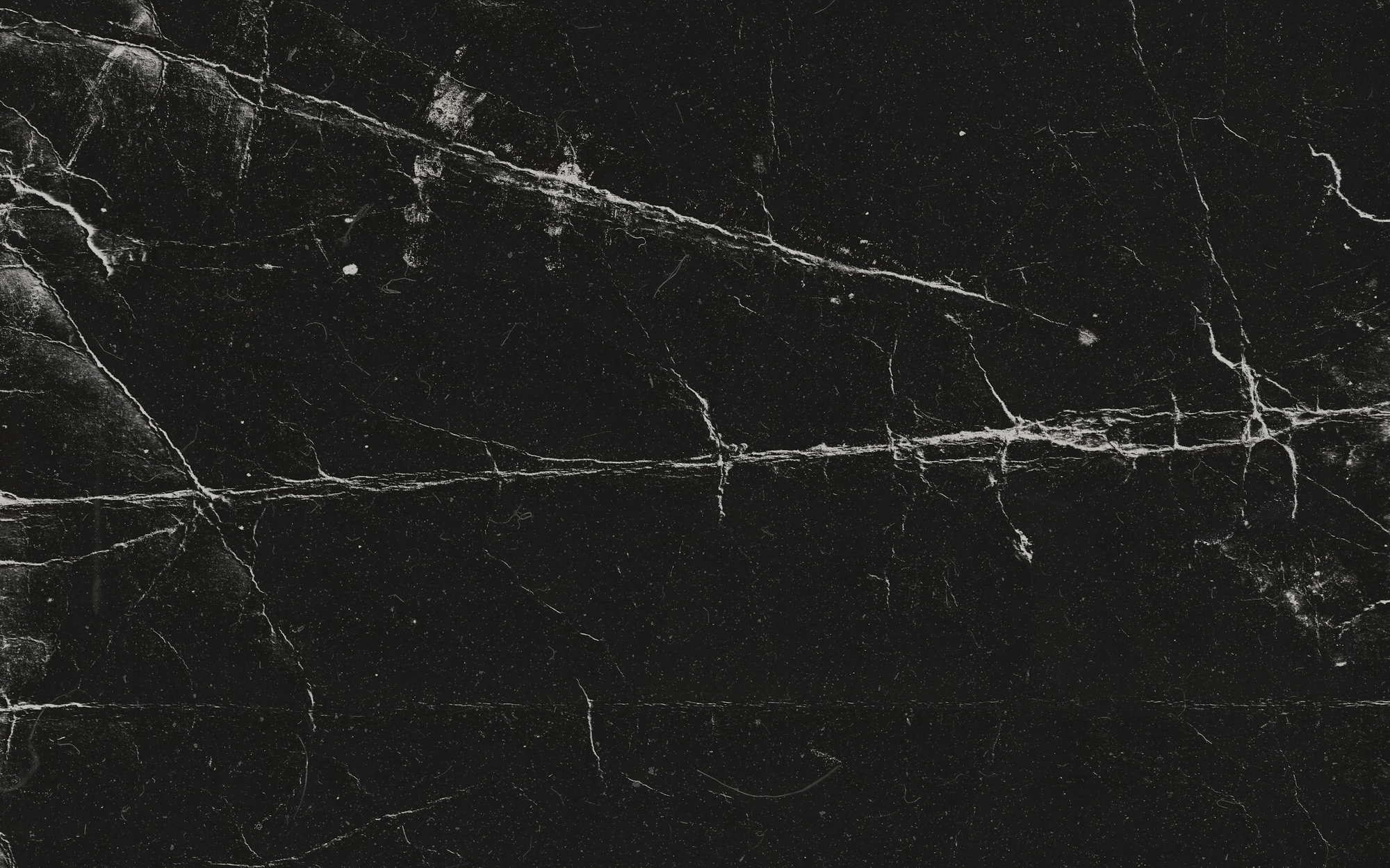 Gros plan sur une surface de marbre sombre traversée par une lumière rasante.